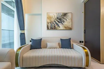 a living room with a couch with blue pillows at Superhost- 1BR Near Miracle Garden, Pool and Gym, Balcony Arjan in Dubai