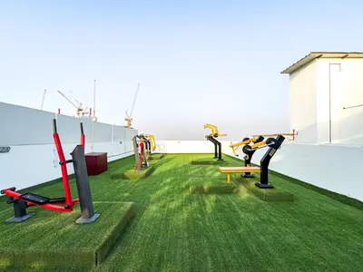 a gym on the roof of a building with green grass at Superhost- 1BR Near Miracle Garden, Pool and Gym, Balcony Arjan in Dubai