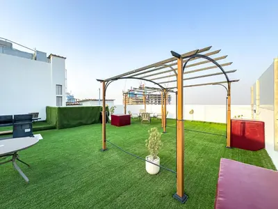 an arbor on the roof of a building with green grass at Superhost- 1BR Near Miracle Garden, Pool and Gym, Balcony Arjan in Dubai