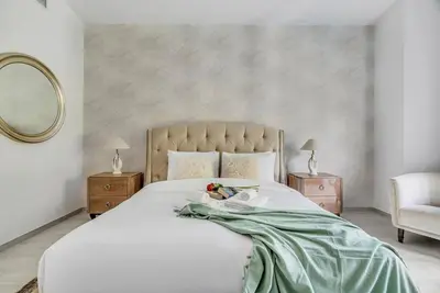 a bedroom with a large white bed with a green blanket at DAYF-NIL Lux 5-BR Villa with Pool & Piano - Green Community in Dubai