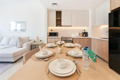 a kitchen and a living room with a table and chairs at FAM Living - Elegant 2BR with Park & Creek Panorama in Dubai