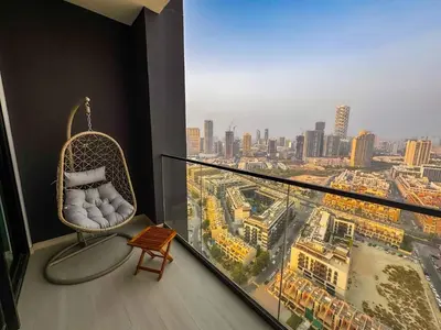 a balcony with a rattan chair and a view of a city at 2 Bed, Private Pool, Big Terrace, Solysian Stay in Dubai