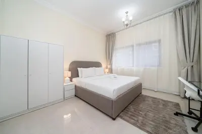a white bedroom with a bed and a window at Bright and Stylish 2 Bed Home Opposite Circle Mall in Dubai