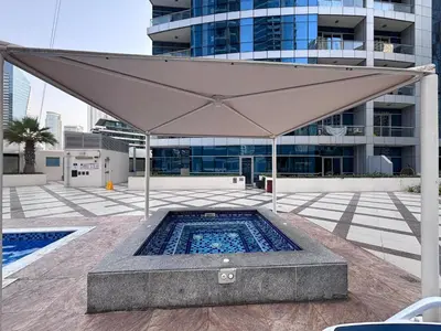 a large umbrella over a pool in front of a building at Premium 1BR in Dubai Marina King Bed, Marina View, Near JBR, Beach & Vibrant Nightlife in Dubai