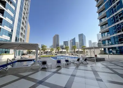 a patio with a pool and chairs and buildings at Premium 1BR in Dubai Marina King Bed, Marina View, Near JBR, Beach & Vibrant Nightlife in Dubai