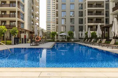 a swimming pool in a building with chairs and umbrellas at Maison Privee - Charming Urban Escape with Resort-Style Facilities in Dubai