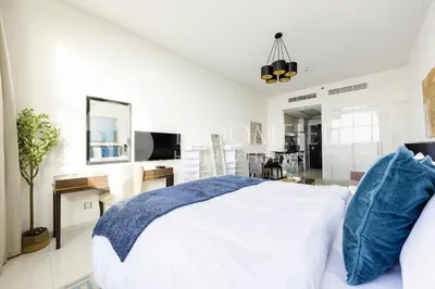 a white bedroom with a bed and a desk at Bloomfields Elegant Stu Damac Ghalia in Dubai