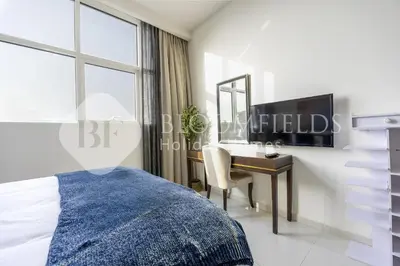 a bedroom with a bed and a desk with a mirror at Bloomfields Elegant Stu Damac Ghalia in Dubai