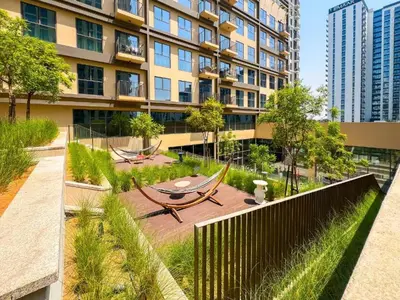 a building with a garden with a table and benches at Stylish 1BR in Socio Pool, Cinema & Game Lounge in Dubai