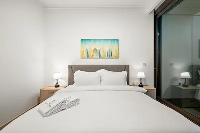 a bedroom with a large white bed with two lamps at FIRST CLASS 3BR Stunning Burj Khalifa View in Dubai