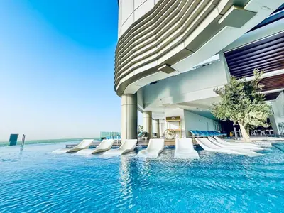 a swimming pool with white chairs in a building at 64th Floor Infinity Pool 2BR Best Burj Khalifa View in Dubai