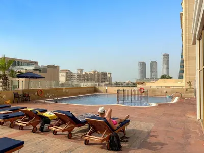 a person laying in lounge chairs near a swimming pool at FIRST CLASS1BR Sea View and Near Beach and Tram in Dubai