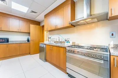 a large kitchen with wooden cabinets and stainless steel appliances at Spacious 4BR Plus Maids Villa, Near Avenue Mall, Cycle Park & Sports Complex - 15 Mins to Downtown Dubai, Nad Al Shiba Third by Deluxe Holiday Homes in Dubai