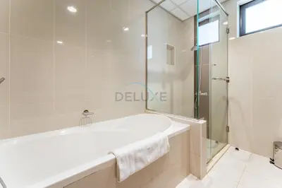 a white bathroom with a tub and a glass shower at Spacious 4BR Plus Maids Villa, Near Avenue Mall, Cycle Park & Sports Complex - 15 Mins to Downtown Dubai, Nad Al Shiba Third by Deluxe Holiday Homes in Dubai
