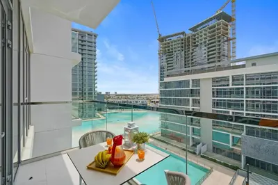 a balcony with a table and chairs and a view of a building at DAYF-JFH Spacious Apartment 4 PAX with Magical Lagoon Views in Dubai