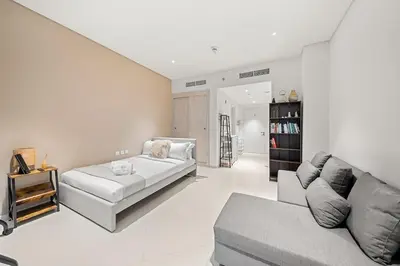 a white living room with a couch and a table at FIRST CLASS Studio Infinity Pool and Luxe Vibes in Dubai