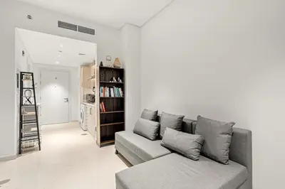 a living room with a couch and a book shelf at FIRST CLASS Studio Infinity Pool and Luxe Vibes in Dubai