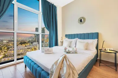 a bedroom with a large bed and a large window at FIRST CLASS Studio Cozy Vibes and Stylish Escape in Dubai
