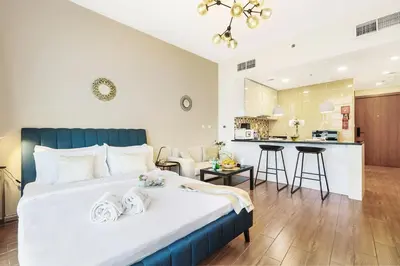 a bedroom with a large bed and a kitchen at FIRST CLASS Studio Cozy Vibes and Stylish Escape in Dubai