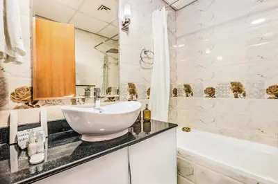 a white bathroom with a sink and a bath tub at FIRST CLASS Studio Cozy Vibes and Stylish Escape in Dubai
