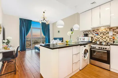 a kitchen with white cabinets and a counter with a dishwasher at FIRST CLASS Studio Cozy Vibes and Stylish Escape in Dubai