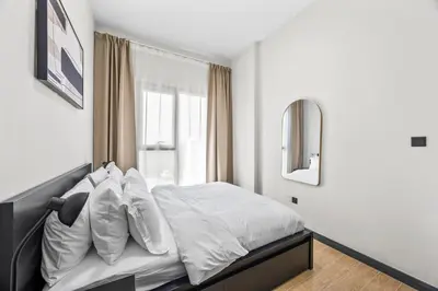 a bedroom with a bed with white sheets and a window at Cosy Apartment in Dubailand near Global Village in Dubai