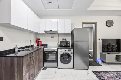 a kitchen with a refrigerator and a dishwasher at Cosy Apartment in Dubailand near Global Village in Dubai