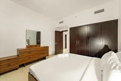 a bedroom with a large white bed and a mirror at FIRST CLASS 1BR Modern Urban Retreat in Dubai