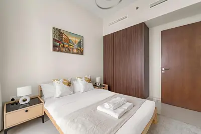 a bedroom with a large bed and a wooden door at Cozy 1BR at Reva Residences in Dubai