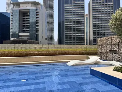 a swimming pool in a city with tall buildings at Cozy 1BR at Reva Residences in Dubai