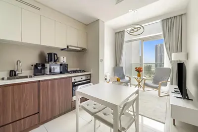 a kitchen and living room with a table and chairs at Cozy 1BR at Reva Residences in Dubai