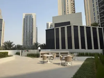 a patio with tables and chairs in front of buildings at Island Park Comfort Stay in Dubai