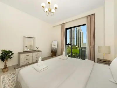 a white bedroom with a large bed and a window at Island Park Comfort Stay in Dubai