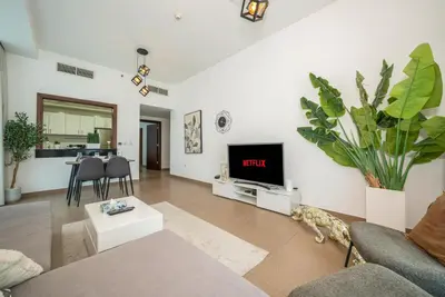a living room with a couch and a tv on a wall at Luxury 1BR with Pool, Gym Canal & Burj Khalifa view in Dubai