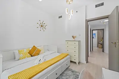 a white bedroom with a large bed and a dresser at Stylish Apartment with Pool, Gym and Skyline View Dubai Gate in Dubai