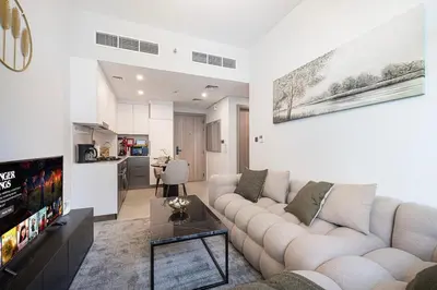 a living room with a white couch and a tv at Downtown culture village escape in Dubai