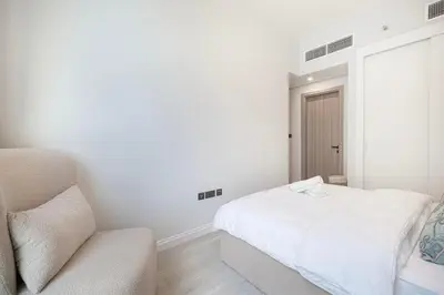 a white bedroom with a bed and a couch at Downtown culture village escape in Dubai