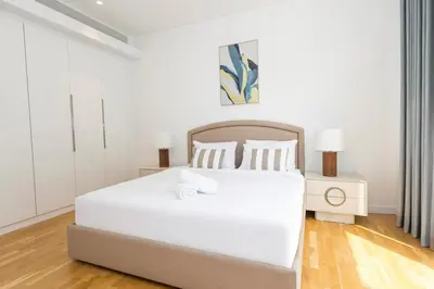 a white bedroom with a large white bed and wooden floors at Spacious Luxury 1BR Modern Design Bluewaters in Dubai