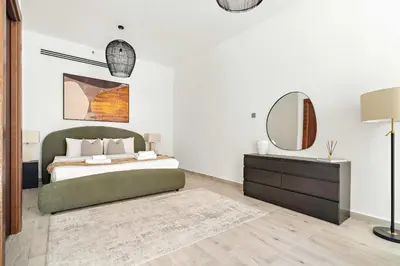 a bedroom with a bed and a mirror and a dresser at Silkhaus Classic 1BDR Stay in Jumeirah Village in Dubai