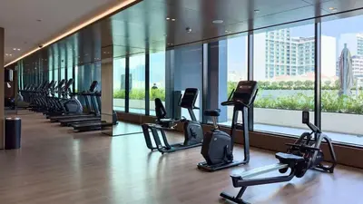 a gym with a row of cardio machines in a building at TRPS - Binghatti Onyx JVC - Luxury 2BR with Private Pool in Dubai