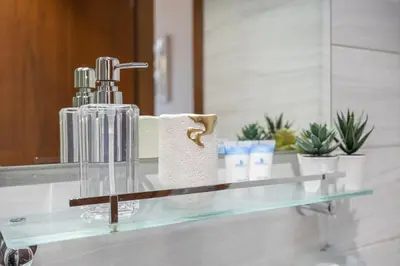 a glass bathroom counter with a towel dispenser and a mirror at Dunya Tower Downtown 1BR Balcony Pool View 2Min to Dubai Mall in Dubai