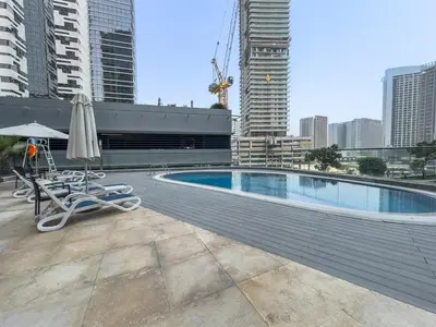 a swimming pool with umbrellas and chairs on a building at Dunya Tower Downtown 1BR Balcony Pool View 2Min to Dubai Mall in Dubai