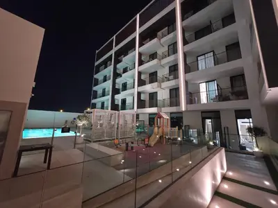 a building with a swimming pool at night at Binghatti Dusk Studio with Gym &Pool in Dubai