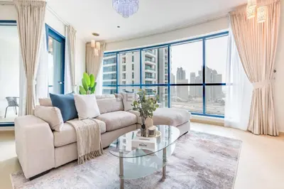 a living room with a couch and large windows at Spacious 1BR Overlooking City Skyline and Marina, Next to JLT Lakefront, Just Minutes to Metro, Jumairah Bay Tower X1, JLT by Deluxe Holiday Homes in Dubai