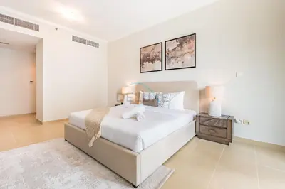 a white bedroom with a bed and a night stand at Spacious 1BR Overlooking City Skyline and Marina, Next to JLT Lakefront, Just Minutes to Metro, Jumairah Bay Tower X1, JLT by Deluxe Holiday Homes in Dubai