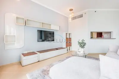 a white living room with a tv and a couch at Spacious 1BR Overlooking City Skyline and Marina, Next to JLT Lakefront, Just Minutes to Metro, Jumairah Bay Tower X1, JLT by Deluxe Holiday Homes in Dubai