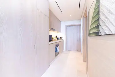 a kitchen with white cabinets and a television on a wall at Scenic Studio at Palm Tower in Dubai