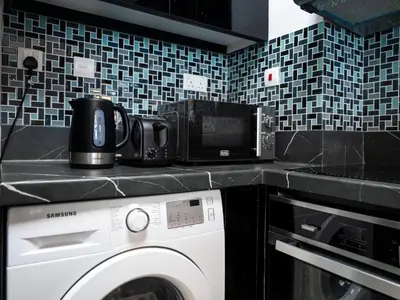 a kitchen with a washing machine and a microwave at Bright & Stylish Studio with Marina Views in Dubai