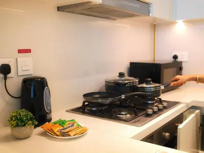 a person is cooking on a stove in a kitchen at Burj Khalifa View Luxe 2BR x Connected to Dubai Mall in Dubai