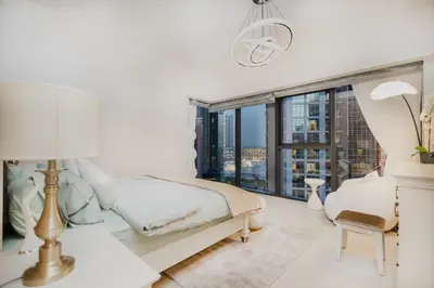 a white bedroom with a bed and a large window at Iconic Views 2BR Burj Khalifa and Fountain in Dubai